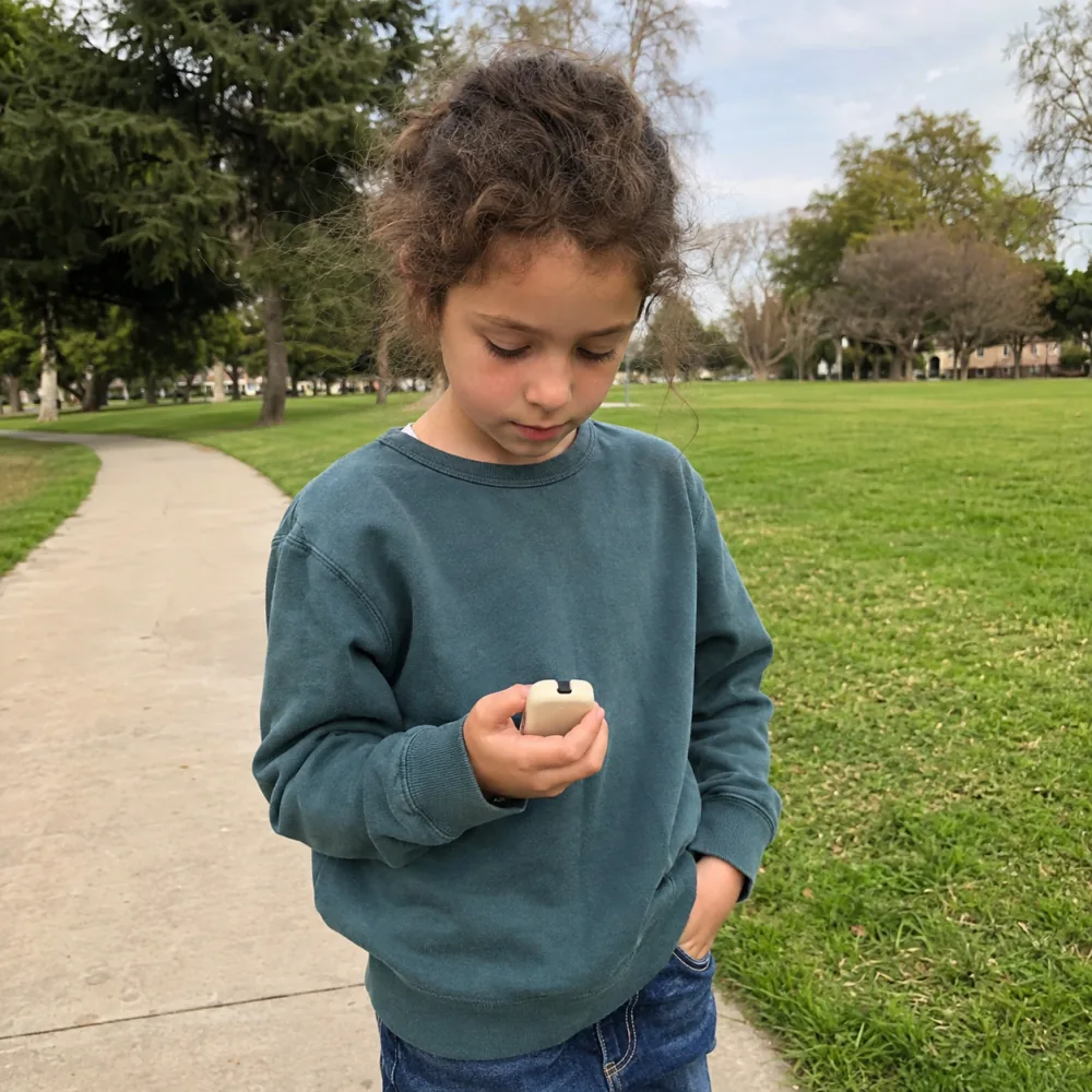 A child holding ReadyChime on a path in a park